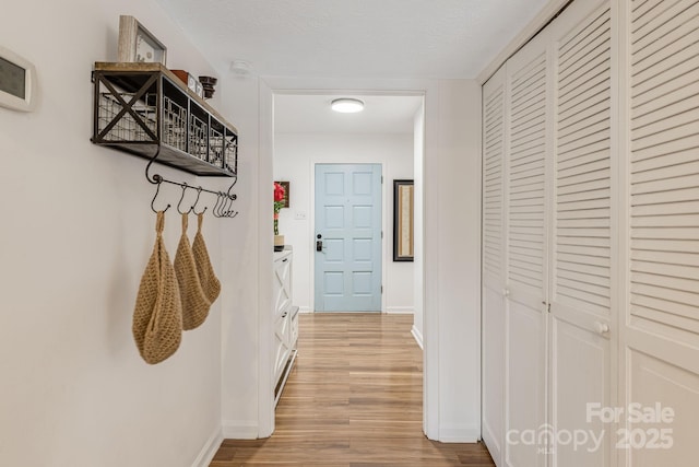 hallway with a textured ceiling and light hardwood / wood-style floors