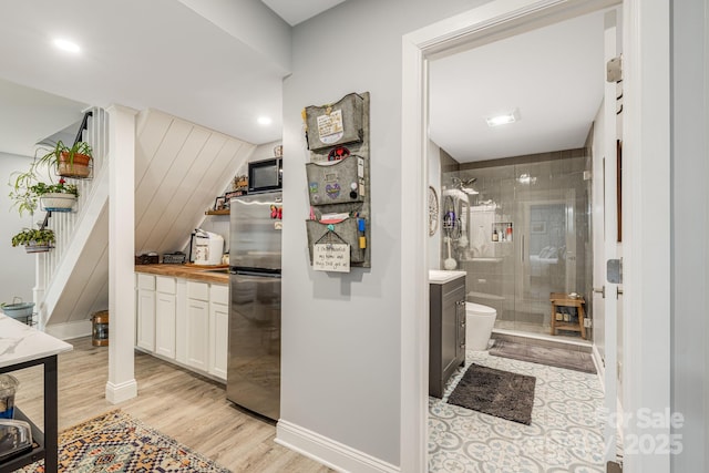 interior space featuring wooden counters, white cabinets, stainless steel refrigerator, and light hardwood / wood-style flooring