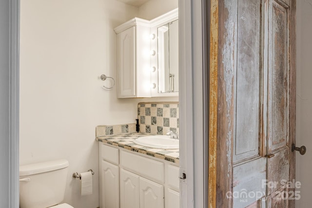 bathroom featuring tasteful backsplash, vanity, and toilet