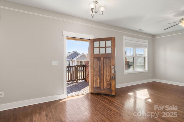 interior space with ceiling fan with notable chandelier and dark hardwood / wood-style floors