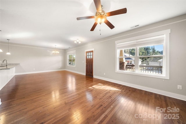 unfurnished living room with dark wood-type flooring and ceiling fan with notable chandelier