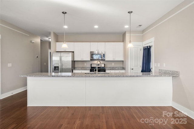 kitchen with white cabinetry, appliances with stainless steel finishes, pendant lighting, and light stone counters