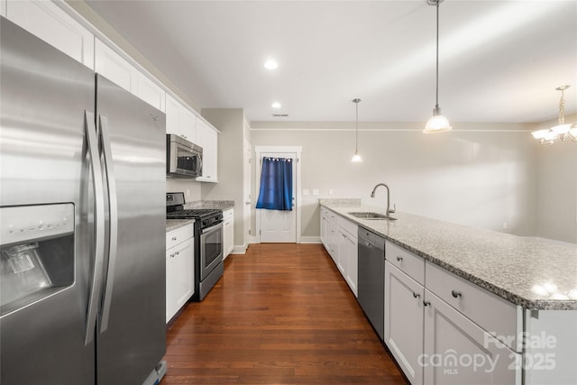 kitchen featuring sink, appliances with stainless steel finishes, white cabinetry, light stone counters, and decorative light fixtures