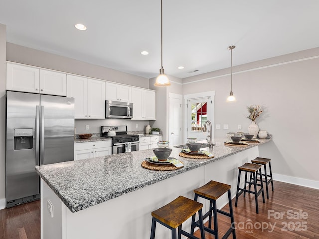 9 Hyde Park Pl, Arden, NC 28704 - kitchen with appliances with stainless steel finishes, light stone counters, white cabinetry, a peninsula, and a kitchen bar
