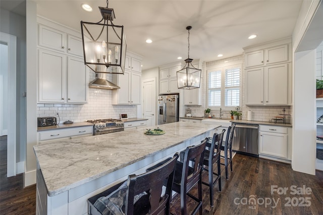 kitchen featuring a spacious island, dark wood-type flooring, white cabinetry, decorative light fixtures, and appliances with stainless steel finishes