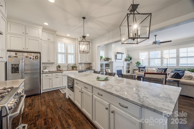 kitchen featuring appliances with stainless steel finishes, white cabinetry, hanging light fixtures, dark hardwood / wood-style floors, and a center island