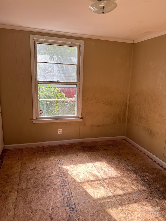 spare room featuring crown molding and wooden walls