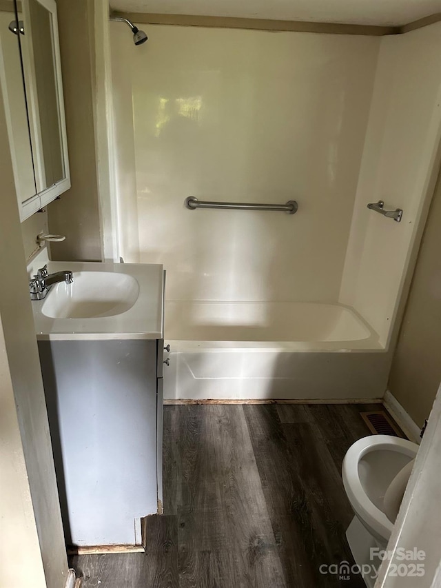 full bathroom with washtub / shower combination, wood-type flooring, toilet, and vanity