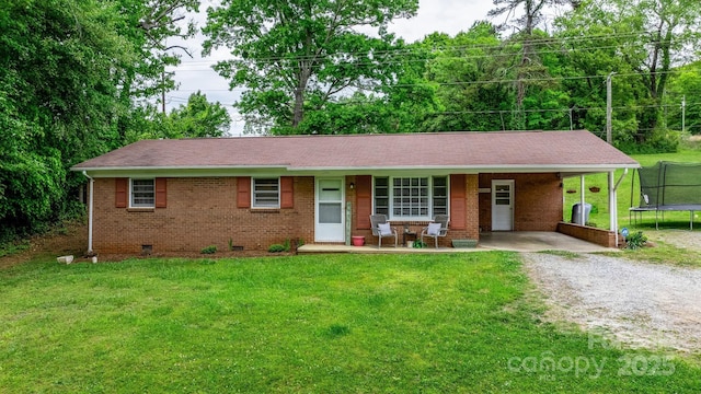 single story home with a trampoline, a front lawn, a carport, and covered porch