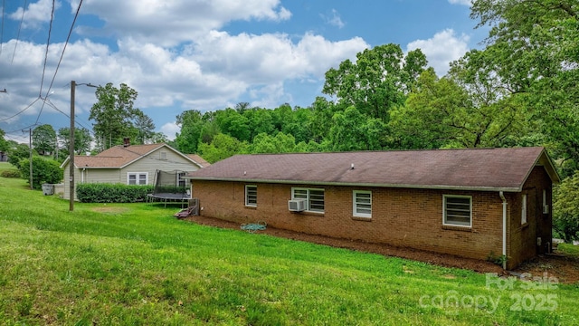 rear view of property featuring a yard, cooling unit, and a trampoline