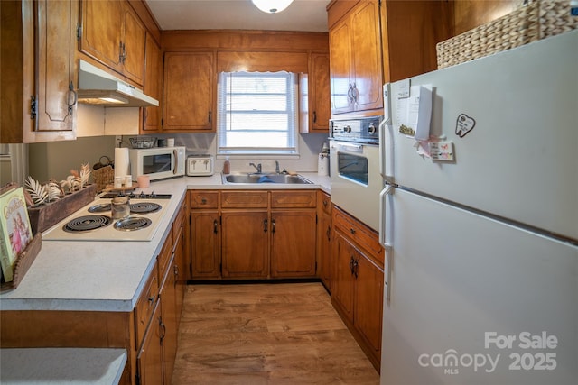 kitchen with sink, white appliances, and light hardwood / wood-style flooring