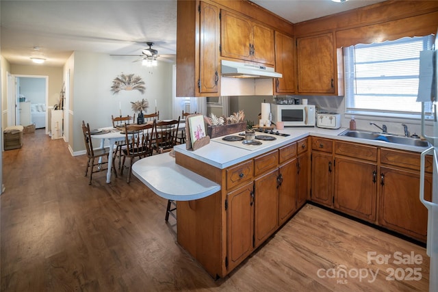 kitchen featuring sink, white appliances, light hardwood / wood-style flooring, kitchen peninsula, and ceiling fan