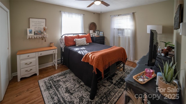 bedroom featuring cooling unit, ceiling fan, light hardwood / wood-style floors, and multiple windows