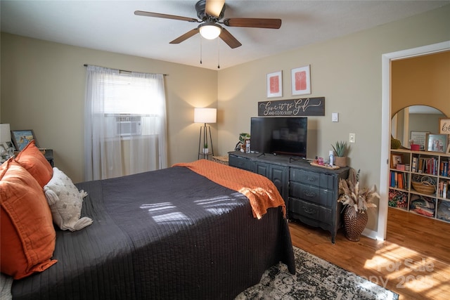 bedroom with cooling unit, ceiling fan, and hardwood / wood-style floors