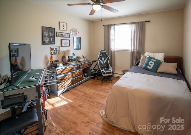 bedroom with a baseboard radiator, hardwood / wood-style floors, and ceiling fan