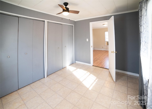 unfurnished bedroom featuring two closets, ornamental molding, and ceiling fan