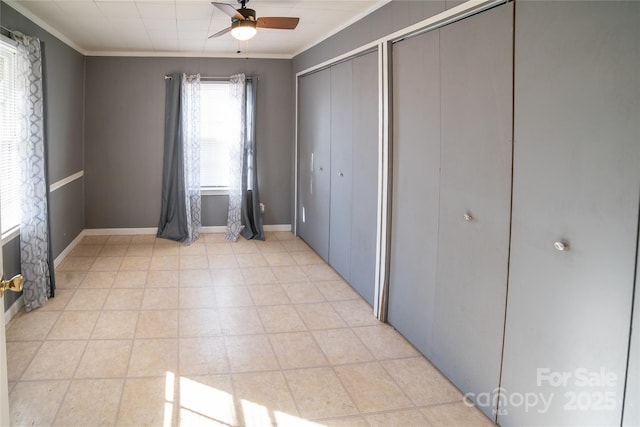 unfurnished bedroom featuring crown molding, ceiling fan, and two closets