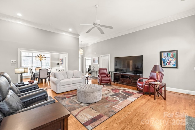 living room featuring hardwood / wood-style flooring, crown molding, and ceiling fan with notable chandelier