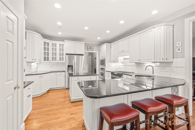 kitchen featuring white cabinetry, sink, a kitchen bar, stainless steel appliances, and crown molding