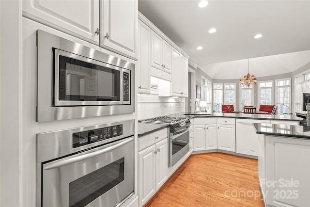 kitchen featuring lofted ceiling, sink, stainless steel appliances, light hardwood / wood-style floors, and white cabinets