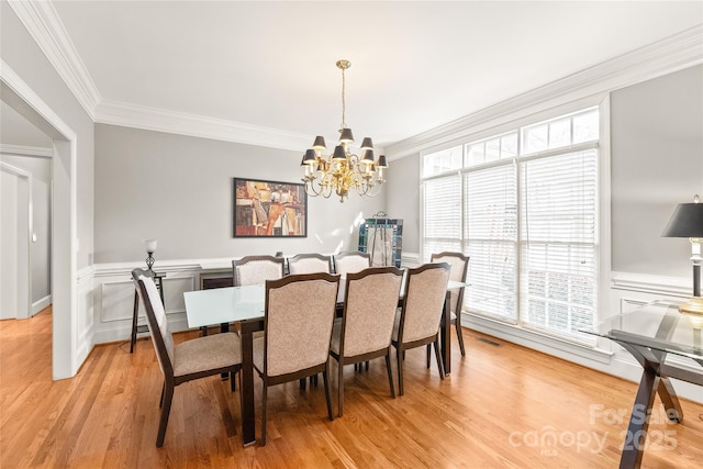 dining area with ornamental molding, light hardwood / wood-style flooring, and a notable chandelier