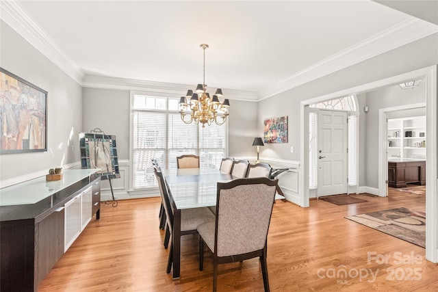 dining area with crown molding, light hardwood / wood-style floors, and a chandelier