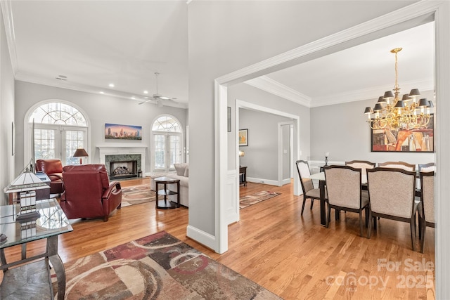 dining room featuring hardwood / wood-style flooring, ornamental molding, plenty of natural light, and a premium fireplace