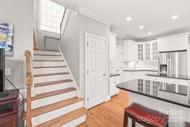 kitchen featuring tasteful backsplash, white cabinetry, ornamental molding, light hardwood / wood-style floors, and stainless steel refrigerator with ice dispenser