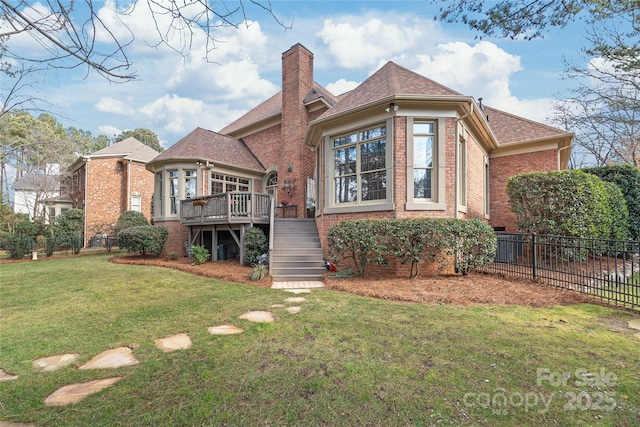 back of property featuring a wooden deck and a lawn