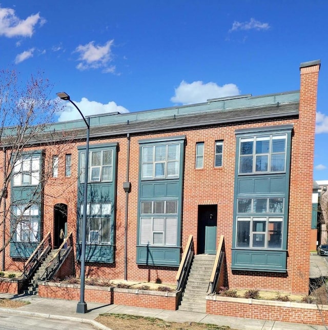 view of front of property with a chimney and brick siding