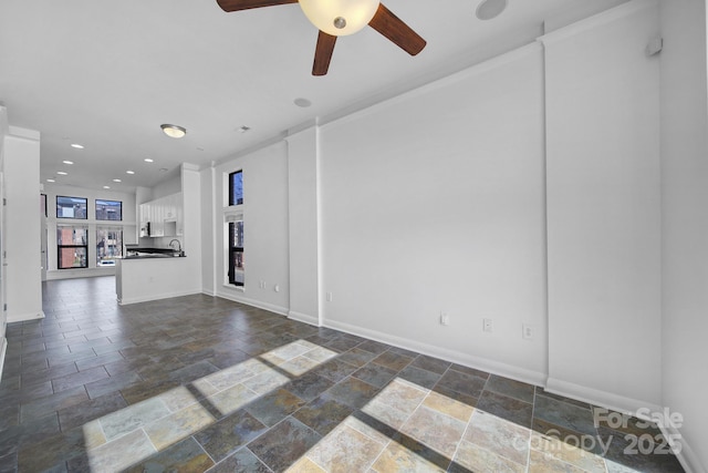 unfurnished room with stone tile floors, baseboards, a ceiling fan, a sink, and recessed lighting