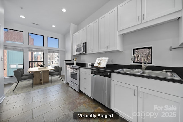 kitchen with visible vents, white cabinets, dark countertops, appliances with stainless steel finishes, and a sink