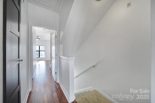 corridor featuring visible vents, dark wood-type flooring, an upstairs landing, and baseboards