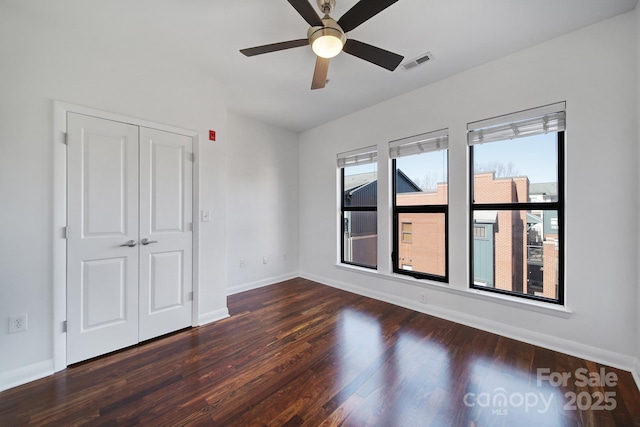 unfurnished bedroom with baseboards, visible vents, ceiling fan, wood finished floors, and a closet