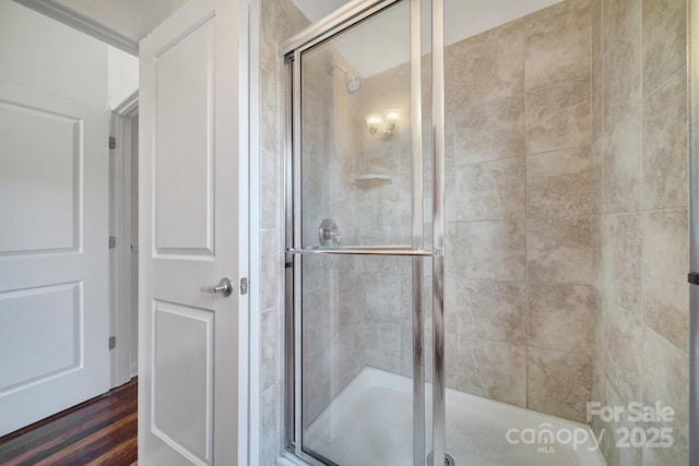 full bath featuring wood finished floors and a shower stall