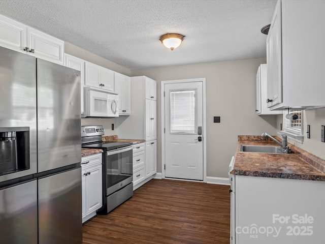 kitchen with sink, white cabinetry, a textured ceiling, appliances with stainless steel finishes, and dark hardwood / wood-style flooring