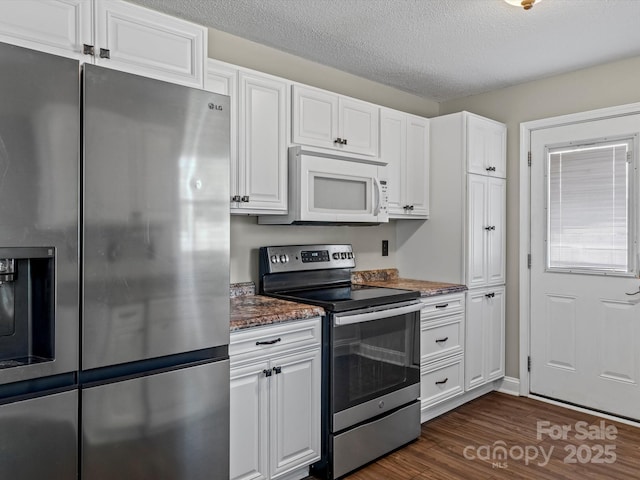 kitchen featuring stainless steel appliances, white cabinetry, dark wood-type flooring, and dark stone countertops