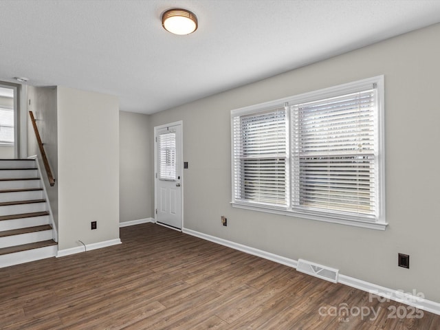 entrance foyer featuring dark wood-type flooring, a textured ceiling, and plenty of natural light