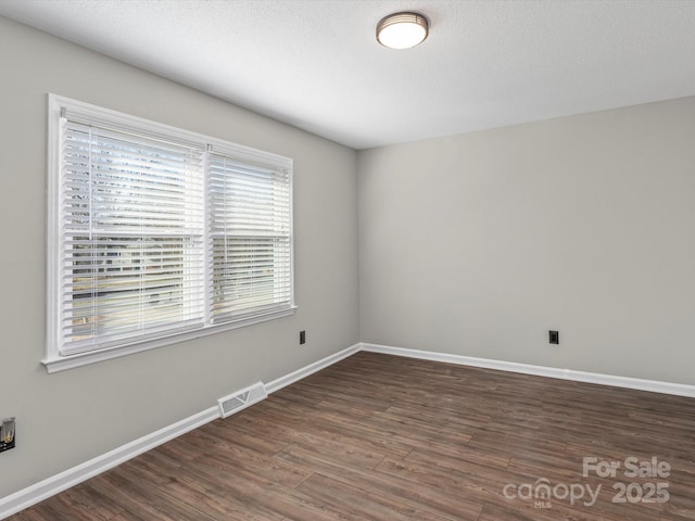 spare room featuring dark hardwood / wood-style floors and a textured ceiling