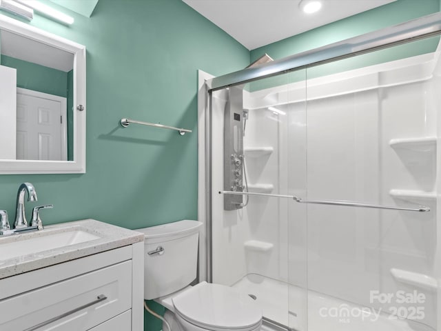 bathroom with an enclosed shower, vanity, and toilet