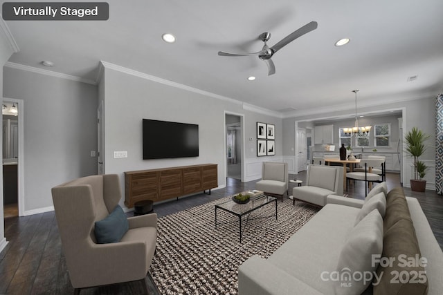 living room with dark hardwood / wood-style flooring, crown molding, and ceiling fan with notable chandelier