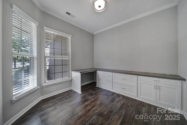 spare room featuring built in desk, ornamental molding, and dark hardwood / wood-style floors