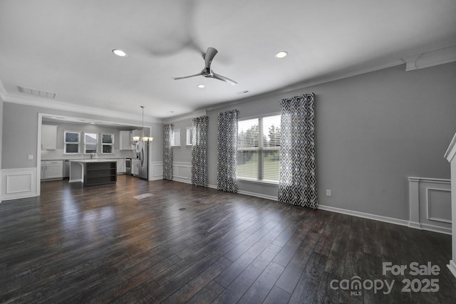 unfurnished living room with sink, ceiling fan with notable chandelier, ornamental molding, and dark hardwood / wood-style floors