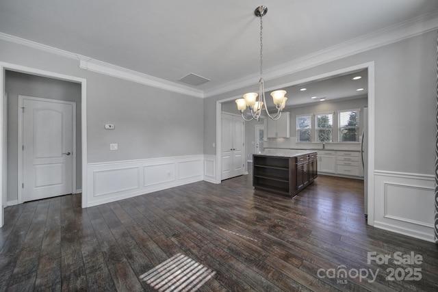 unfurnished dining area featuring crown molding, dark hardwood / wood-style flooring, and a chandelier