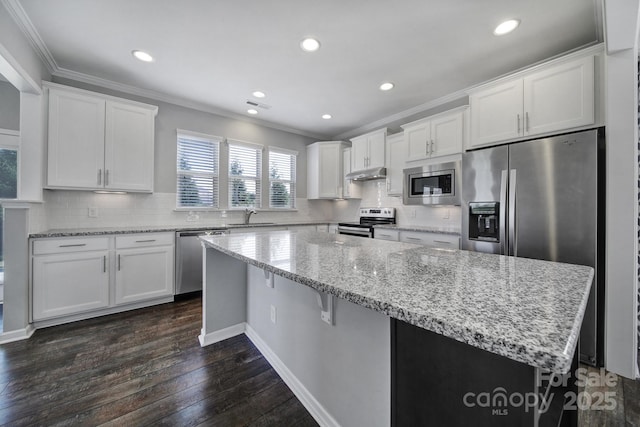 kitchen with dark wood-type flooring, white cabinetry, tasteful backsplash, a kitchen island, and stainless steel appliances