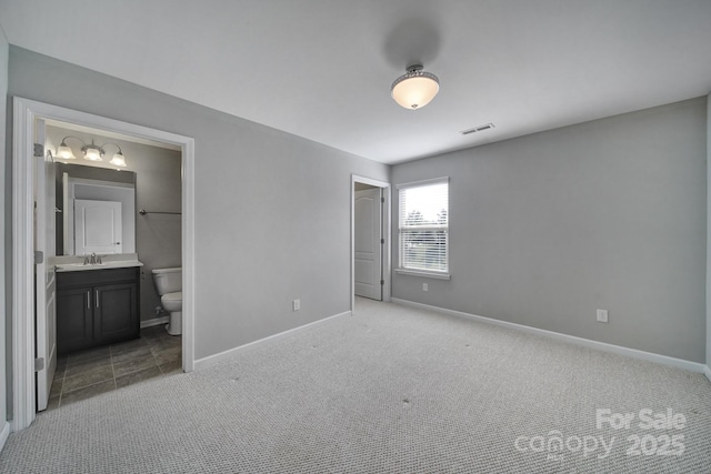 unfurnished bedroom with ensuite bathroom, sink, and light colored carpet