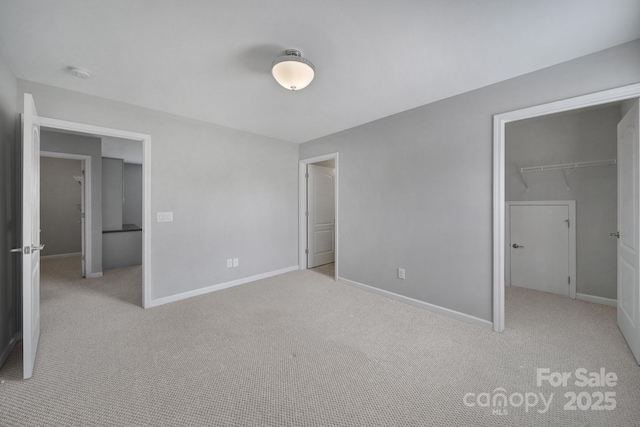 unfurnished bedroom featuring a closet, a spacious closet, and light carpet