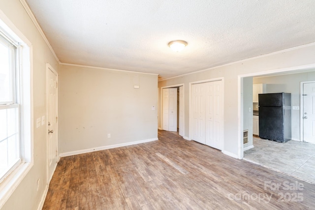 spare room featuring crown molding, hardwood / wood-style floors, a textured ceiling, and a wealth of natural light