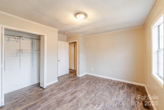 unfurnished bedroom with ornamental molding, hardwood / wood-style floors, a textured ceiling, and a closet