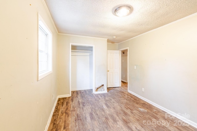 unfurnished bedroom featuring hardwood / wood-style flooring, ornamental molding, a textured ceiling, and a closet